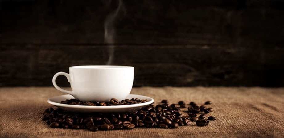 tazzina di caffè fumante con chicchi di caffè